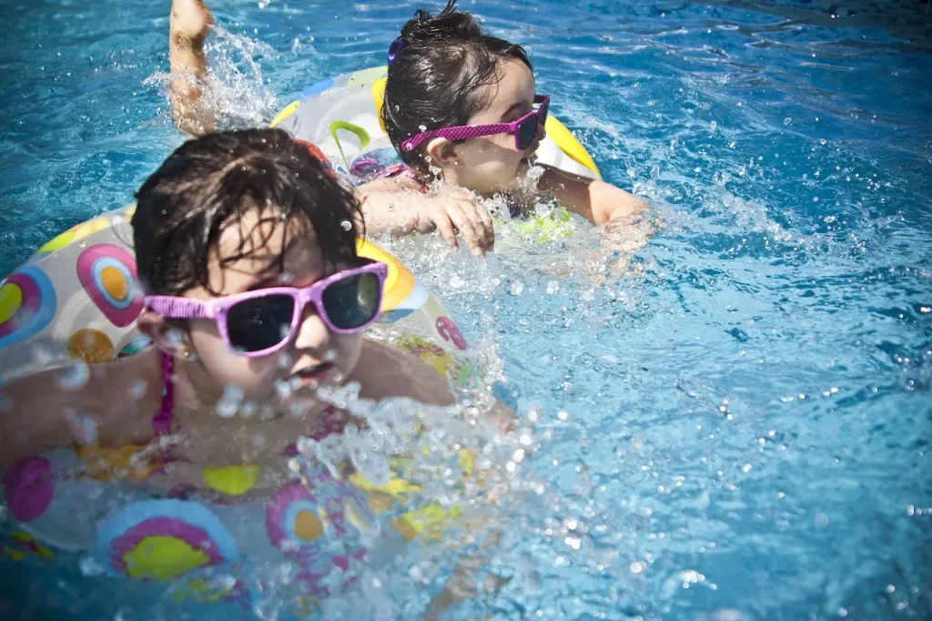 2 Kids enjoying their backyard swimming pool in summer.